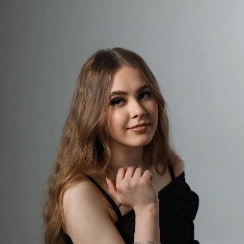 Olga Petrova in a black dress sitting on a gray background